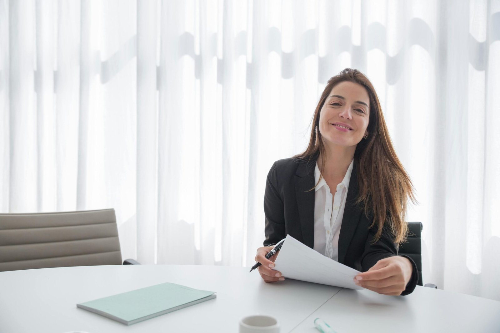 Zwei Personen sitzen an einem Tisch im hellen Büro und besprechen fokussiert Dokumente.